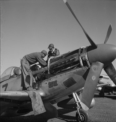 A crew chief and pilot servicing a red-tailed P-51 Mustang engine, 1945