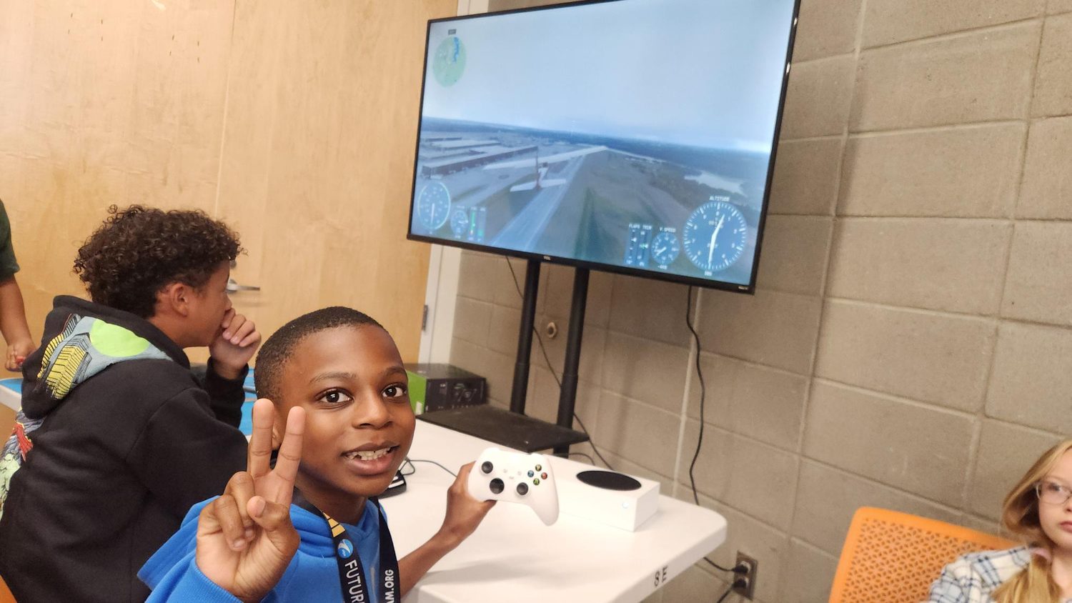 A student gives a peace sign at the flight simulator during the Youth Aviation Academy