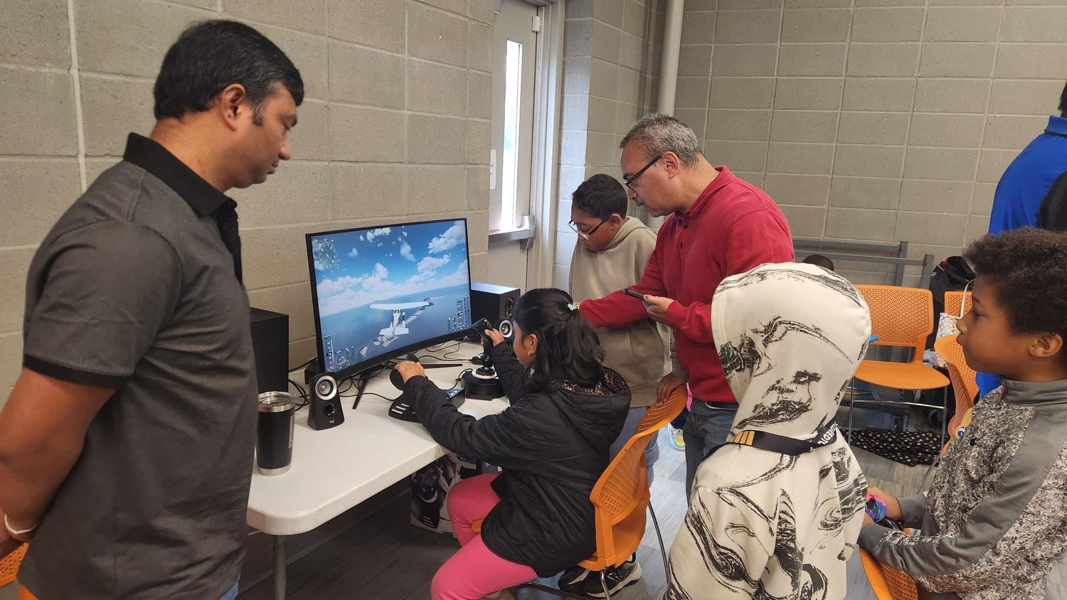 Students flying a desktop flight simulator with volunteers at the Youth Aviation Academy