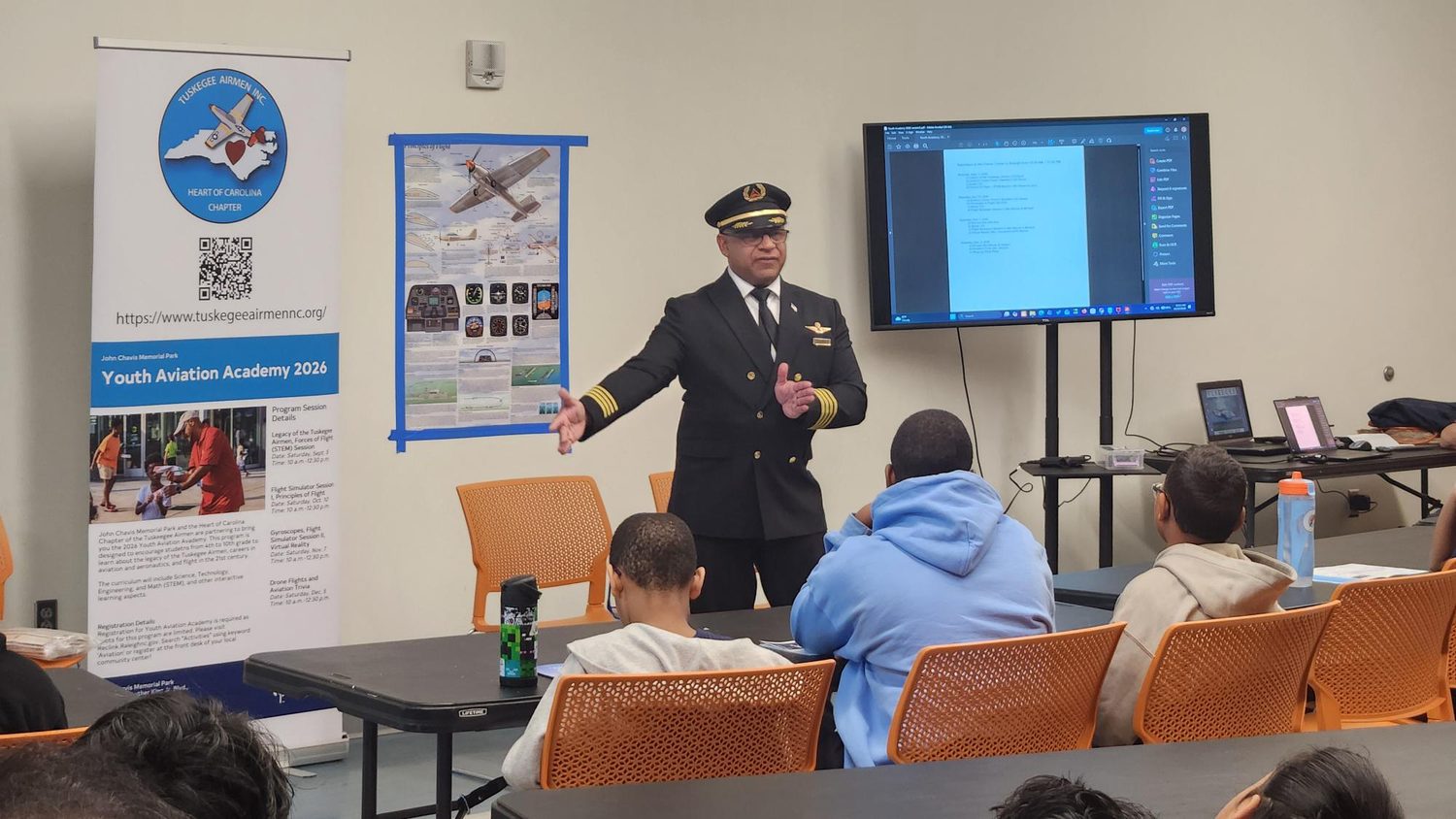 A guest speaker in a pilot uniform discusses aviation career options with students